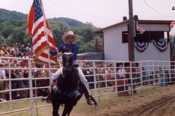 Tammy and the USA flag on horseback at the rodeo